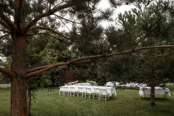 Un parco con alcuni tavoli decorati con sedie accanto. Concetto cena di nozze . — Foto Stock