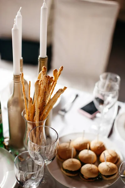 A lots of cutlery is standing on the table alongside with some food and a three candles. — Stock Photo, Image