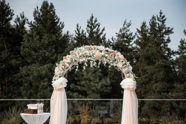 Un arco di fiori con le tende di pesca e un tavolino vicino. Foresta sullo sfondo . — Foto Stock