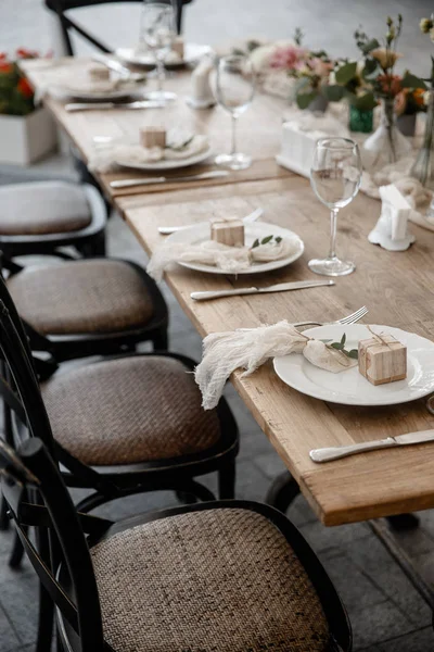 A table with a bunch of cutlery and some wineglasses on it. Some wooden chairs are standing alonside the table. — Stock Photo, Image