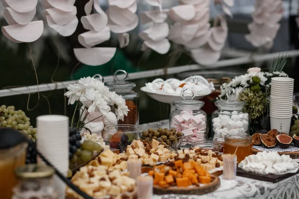 A bunch of desserts and some flower bouquets are standing on a served table. — Stock Photo, Image