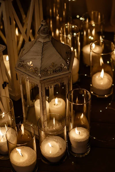 Muitas velas estão queimando dentro dos óculos de vela, juntamente com algumas lanternas . — Fotografia de Stock