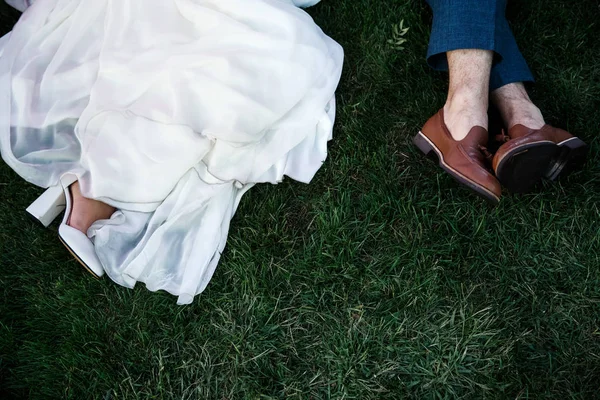Feet of the bride and the groom as they are laying on the lawn. — Stock Photo, Image