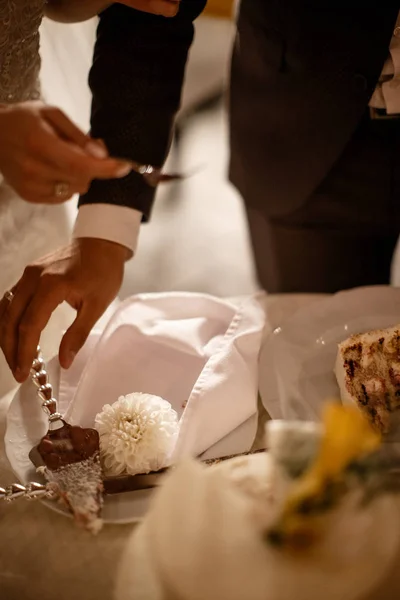 A groom and a bride are using a cutlery to cut a cake in pieces closeup. — Stock Photo, Image