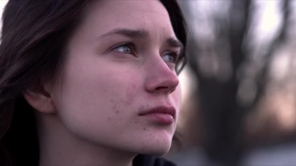 Young girls face closeup. She is looking around with a thoughtful face as the wind waves her hair. — Stock Video