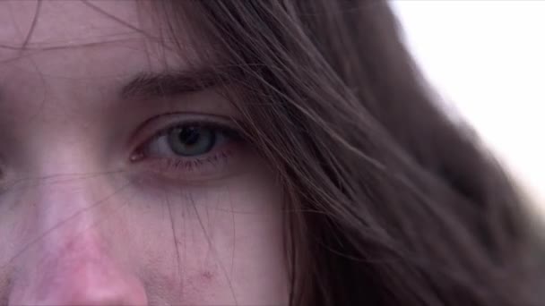 Closeup of a young girls eye, she is looking at the camera. The wind is waving her hair. — Stock Video