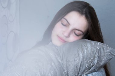 Kız uyuyor, yastığa sarılıyor, rüya görüyor.