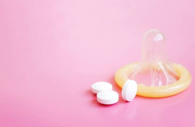 Prezervatif ve pembe bir arka plan üzerinde beyaz hap ile kopya alanı açıldı
