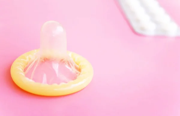 打开避孕套和药丸片剂在粉红色背景与拷贝空间的水泡 — 图库照片