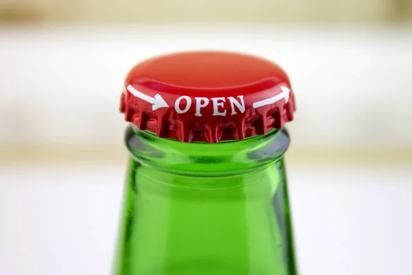 Red cap on the bottle of green glass with a white inscription open