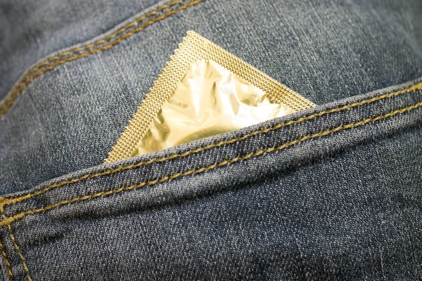 从牛仔裤口袋伸出的避孕套包 图库图片