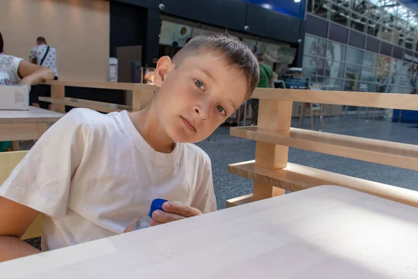 Ένα Preteen Αγόρι Λευκό Shirt Που Κάθεται Στο Τραπέζι Και — Φωτογραφία Αρχείου