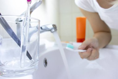 O iki diş fırçası, diş fırçası arka plan üzerinde bulanık kadınla ile açık cam.
