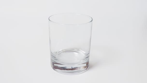 女性の手が白いテーブル それとガラスを離陸に純粋な水を注いでに透明な空のグラスを置く — ストック動画