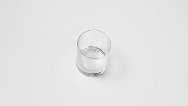 女性の手は それに白いテーブルに透明な空のグラス 純粋な水を注ぐことを入れ赤瓶とガラスを脱いでから — ストック動画