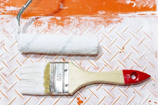 Brush and roller in used paint tray, apartment repair, painting and design concept