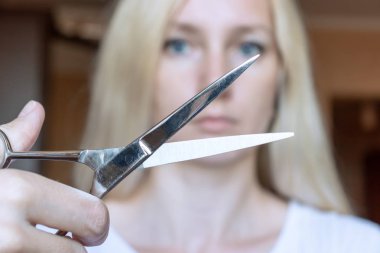 Onun elinde makasla bulanık sarışın kadın.