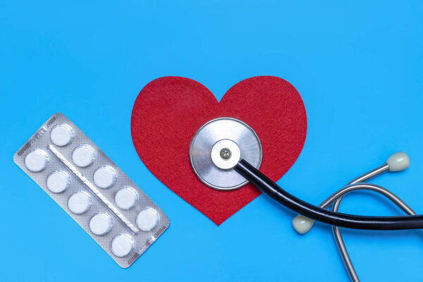 Медицинский, медицинский стетоскоп, шприц, инъекции и таблетки на синем фоне. Здравоохранение или болезни. Кардиологическое лечение сердца
