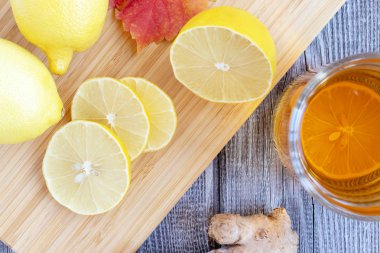 Ahşap bir masa ve doğranmış limon parçaları limonlu zencefil çay.
