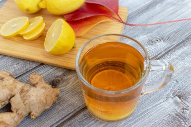 Ahşap bir masa ve doğranmış limon parçaları limonlu zencefil çay.