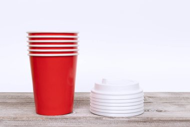 Kırmızı tek kullanımlık kağıt bardak ve kapakları yığını.