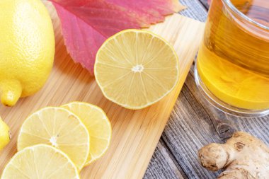 Ahşap bir masa ve doğranmış limon parçaları limonlu zencefil çay.