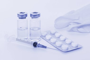 Şırınga, iki şişeleri, tablet ve eldiven tonda ışık mavi.