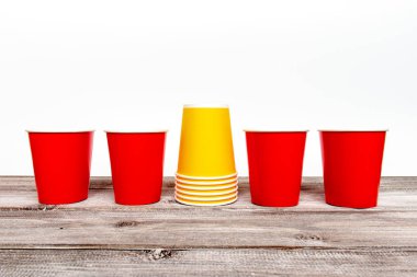 Dört kırmızı ve sarı kağıt tek kullanımlık bardak kahve ve ahşap arka plan üzerinde alkolsüz içecekler için yığını.