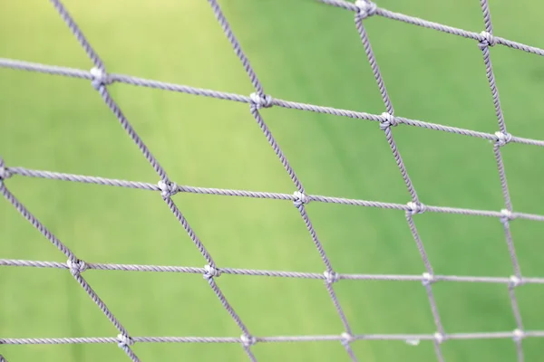 Football net close up on green grass football field background.