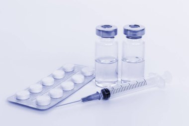 Şırınga, iki şişe ve beyaz zemin üzerine tablet.