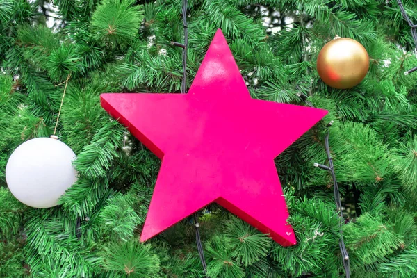 Christmas, New Year green fir tree decorated with glass balls and big pink star.