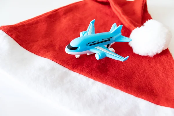 Blue toy plane and red santa hat on white background.