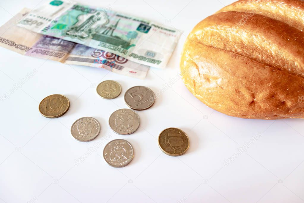 A piece of white bread, coins and paper rubles on the table. The concept of poverty, lack of money for food