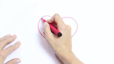 Kadın eli kırmızı kalp marker ile çizim gölgelerini algılar ve bu beyaz masaya geçer.