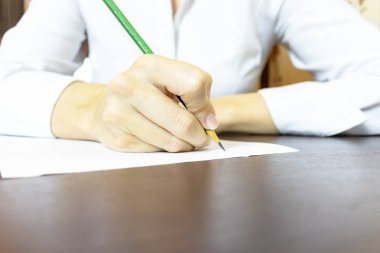 Kadın eli bir şey kağıda yazı kapatın. Tanınmayan iş kadını beyaz gömlekli bir kalemle yazma.