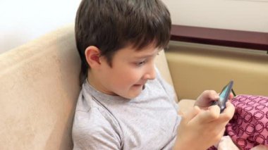 Bir çocuk kanepede oturan ve smartphone oyun