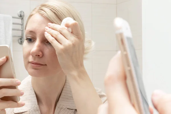 Mujer Limpiando Cara Con Una Almohadilla Algodón Mirando Teléfono Inteligente — Foto de Stock