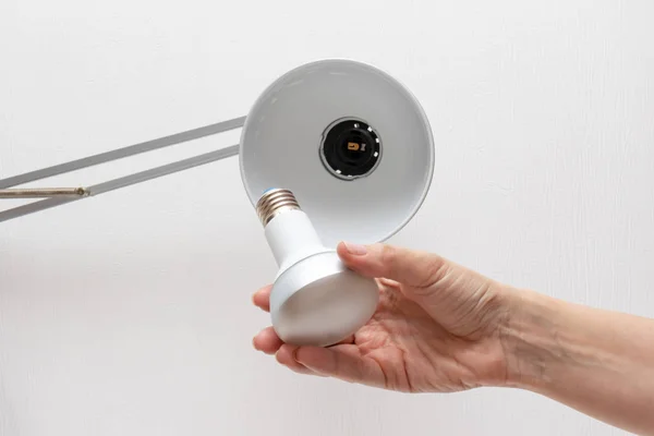 Woman hand changing the lamp bulb, diy household concept.