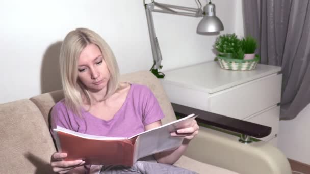 Młoda Blond Kobieta Siedzi Kanapie Zaglądać Folderze — Wideo stockowe