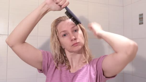 中年中年金发碧眼的女人在浴室用头发刷湿头发 — 图库视频影像