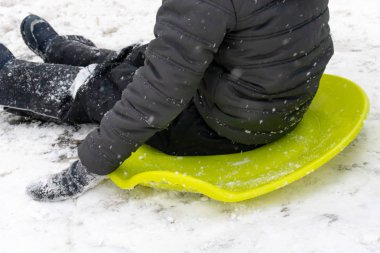 Yedi yaşında bir çocuk ile slayt, yeşil buz kızak üstünde belgili tanımlık tepe aşağı gidiyor. Kış aktiviteleri, rekreasyon ve çocuk eğlence kavramı.