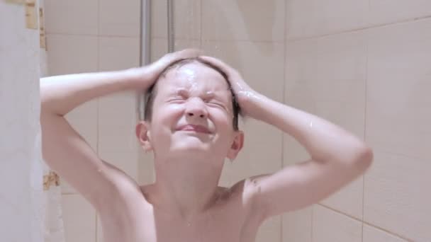 A preteen boy washing his hair with shampoo in the bathroom 
