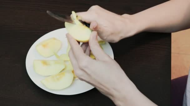 Vrouwelijke handen peeling huid off van een gele appel met een mes — Stockvideo