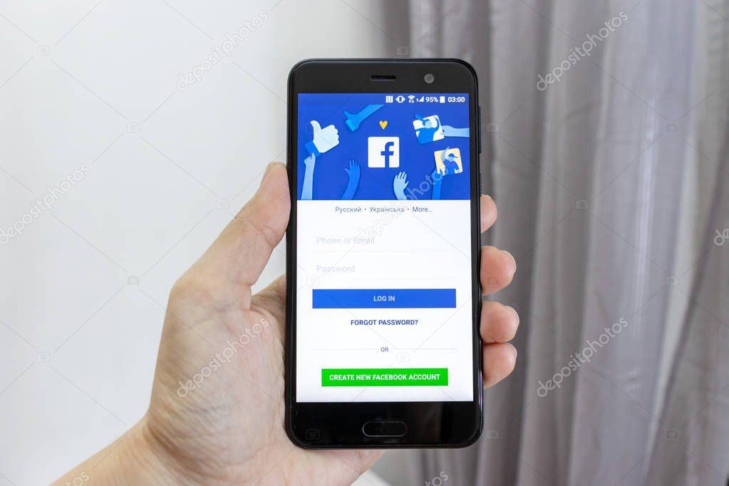 MOSCOW, RUSSIA - JANUARY 08, 2018: Hand holding a smartphone with Facebook application icon on screen. Facebook app icon in play market. Facebook is popular Internet online social media net.