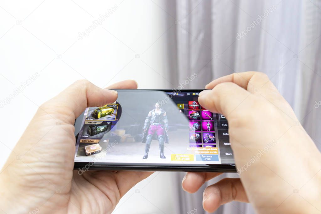 MOSCOW, RUSSIA - JANUARY 08, 2018: Hands holding a smartphone with online multyplayer game PUBG Mobile by battlegrounds.