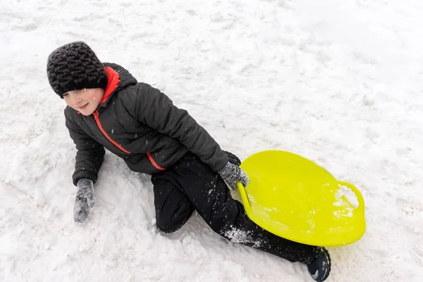 Chlapec Sedmi Let Ležící Sněhu Ruce Držel Zelené Plastové Saně — Stock fotografie
