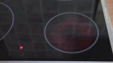 Bir modern cam seramik pişirme panel ve su ile bir tavada koyarak kadın açın