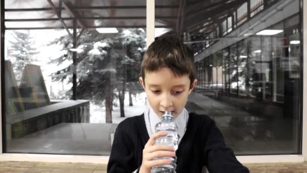 Skolpojke Som Sitter Vid Bordet Tugga Och Dricksvatten Från Plastflaska — Stockvideo