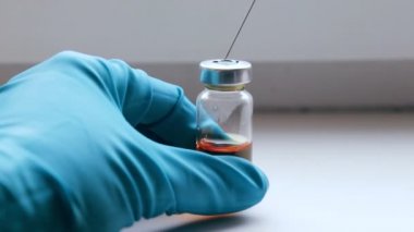 Hemşire kauçuk tıpa ambalajlarda bir şırınga iğneyle delip geçiyor ve sarı bir ilaç çevirir