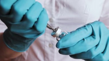 Hemşire kauçuk tıpa ambalajlarda bir şırınga iğneyle delip geçiyor ve sarı bir ilaç çevirir